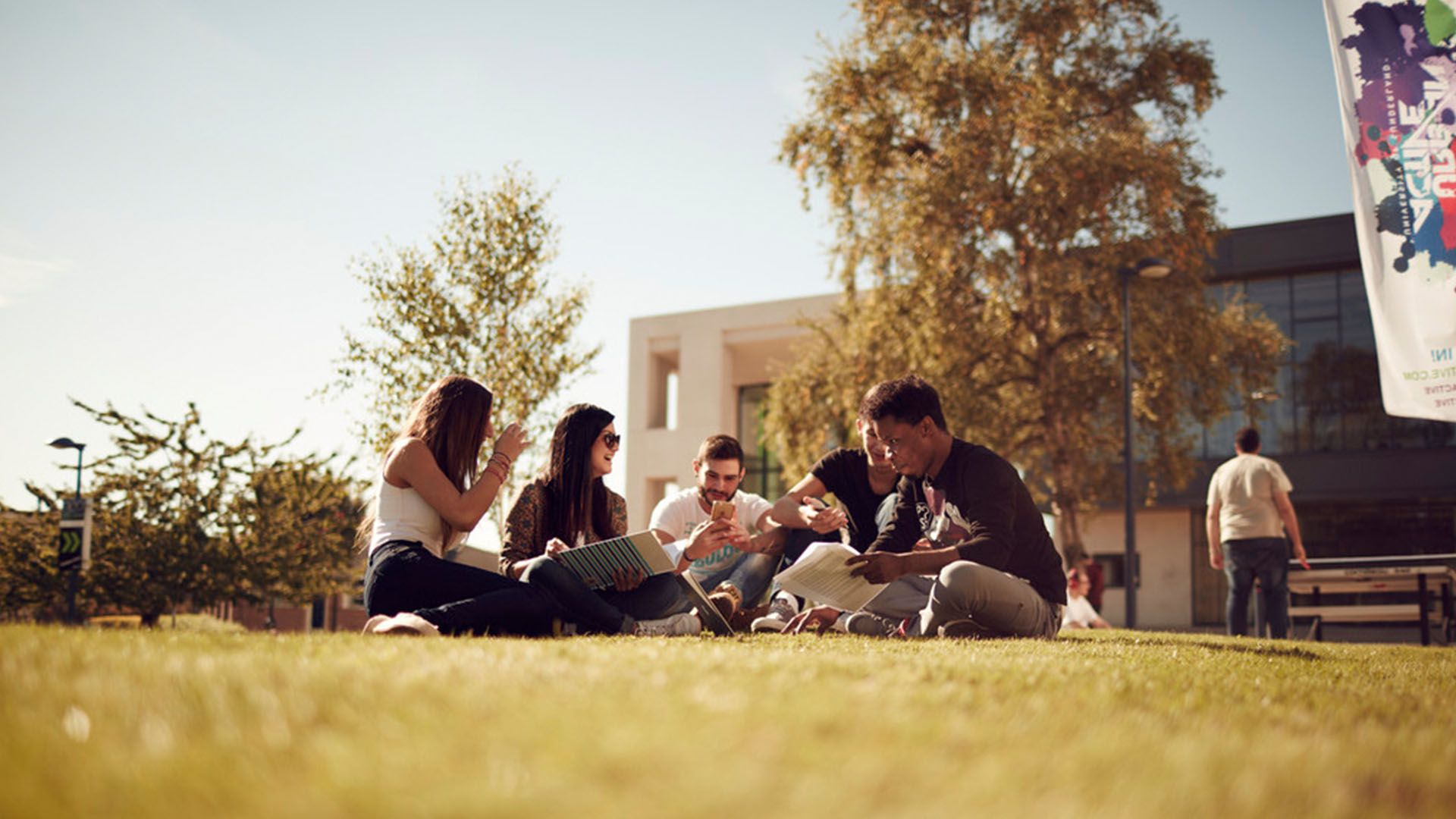 A group of students relaxing on the grass at City Campus on a sunny day