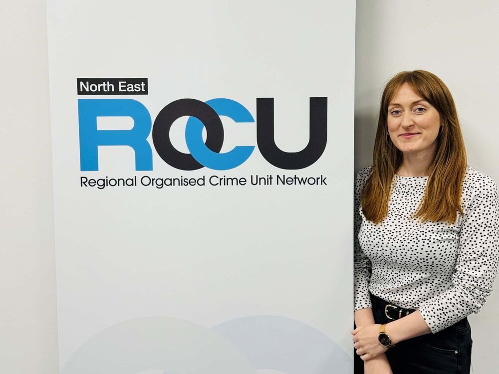 Charlotte standing near a regional orgnised crime sign smiling