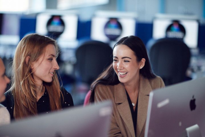 Female students working at computers and laughing together