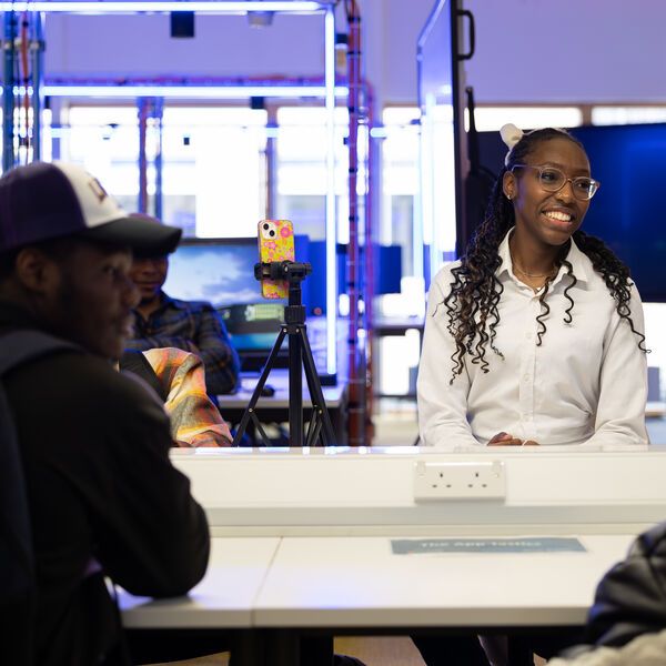 Three computer science students sitting together in the David Goldman Technology Centre, laughing at something that is off camera