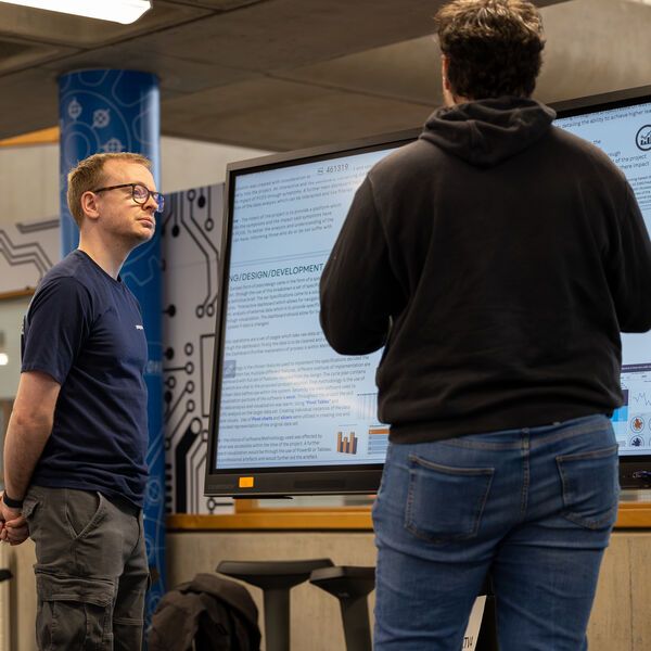 A computer science student presenting their work to an academic who is listening intently