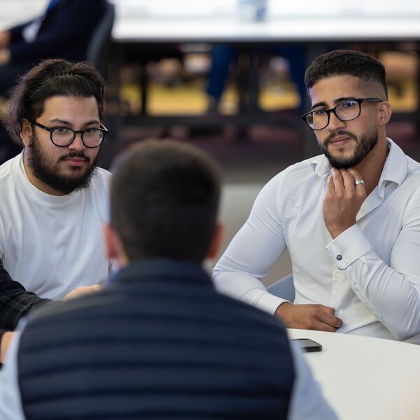 Three students sitting together around a table talking