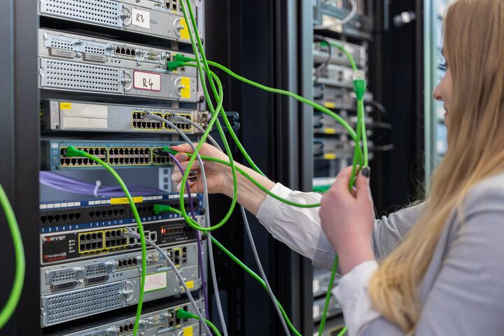 A Cybersecurity student moving cables in a server rack