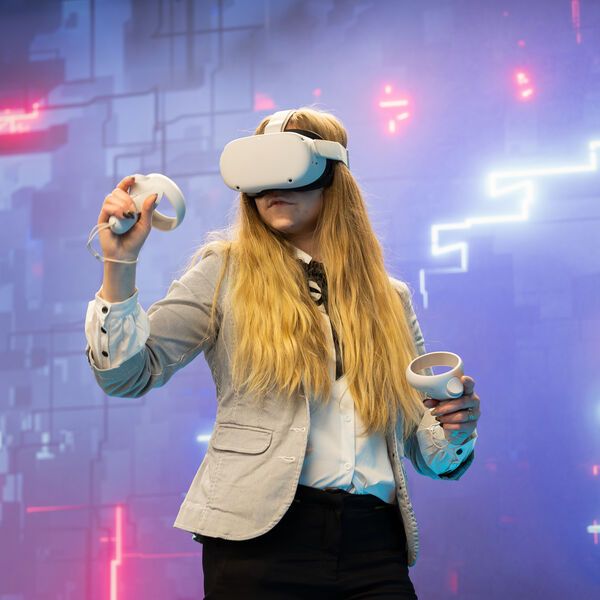 A student wearing a Virtual Reality headset while moving around playing a game