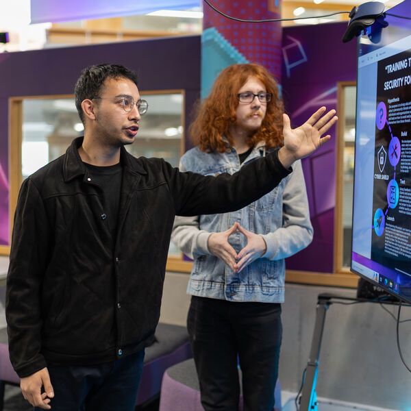 A computer science student presenting their work to another student