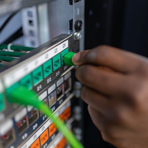 A close up of a student's hand moving cables in a server rack