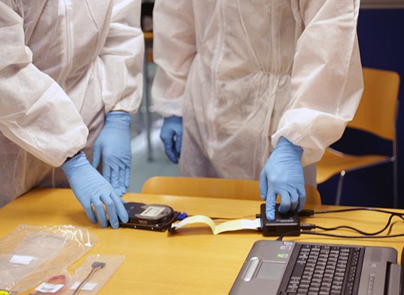Two people in forensic uniform using cybersecurity equipment