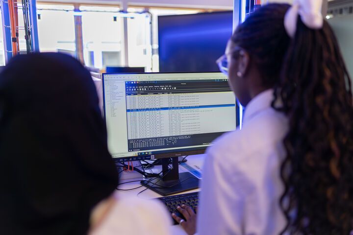Two computer science students sitting together at a computer and working