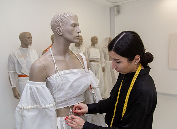 A student pinning an outfit onto a mannequin.