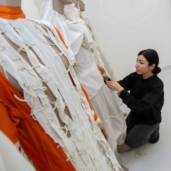 Fashion graduate Hulya Anefi adjusting garments on a mannequin