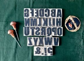 A bird's eye view of some typography stamps laid out on green fabric