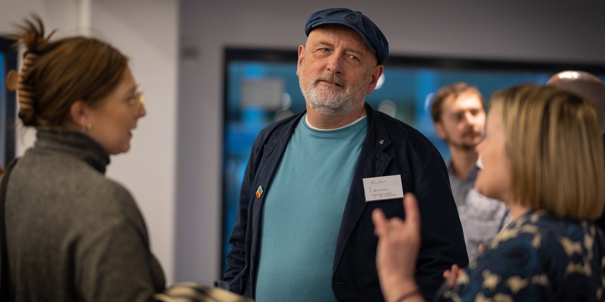 An academic at a conference listening to a person who is standing with them