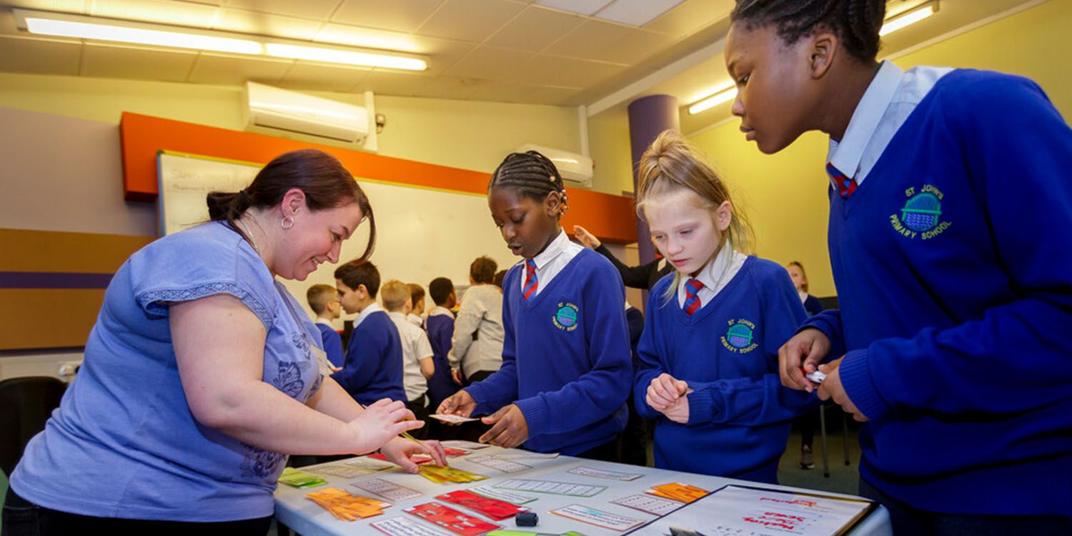 A student teacher assisting secondary school pupils with a maths activity