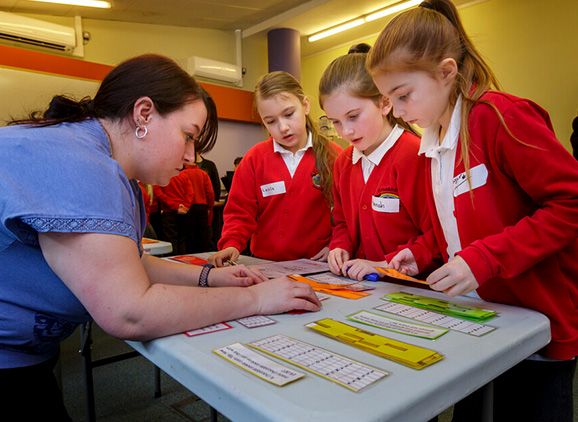 A teacher assisting three primary school aged girls with a maths task