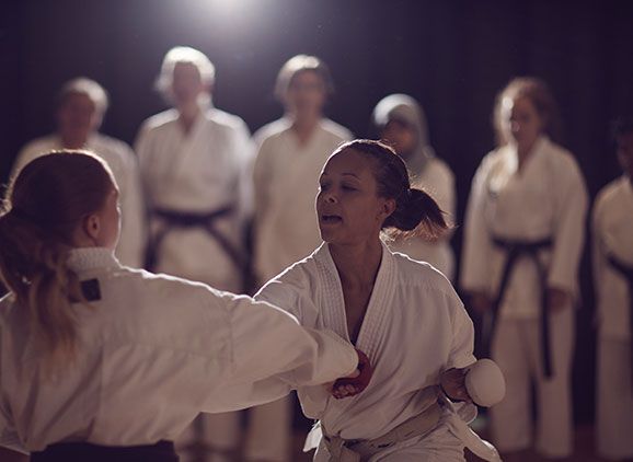 Two students taking part in a karate class while other students watch