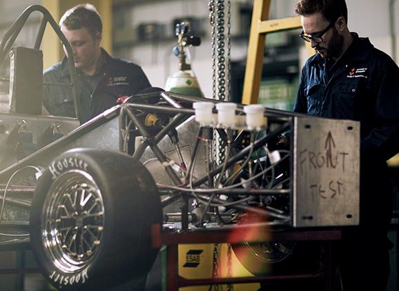 Two students are working on the chassis of the Formula Student car