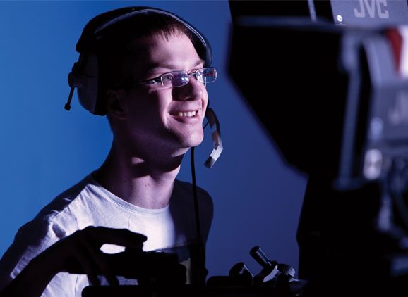 A student wearing a headset, working with filming equipment