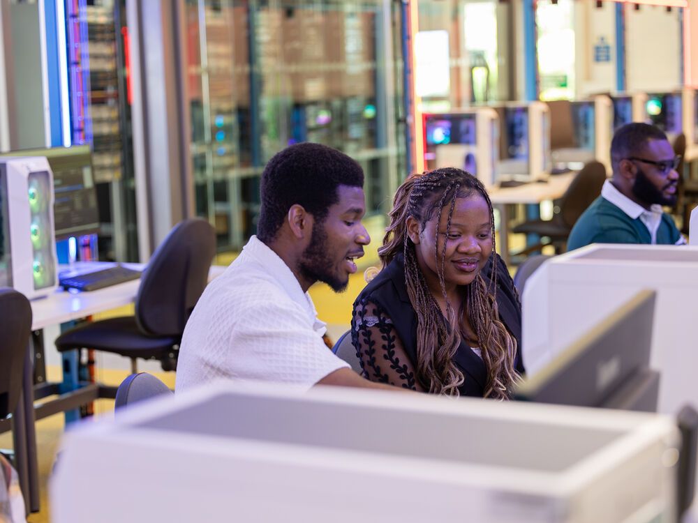 Two computing students working at a computer together in the Cyber Zone