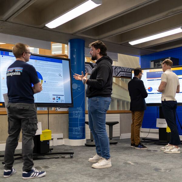 Two computer science students presenting their work to two lecturers