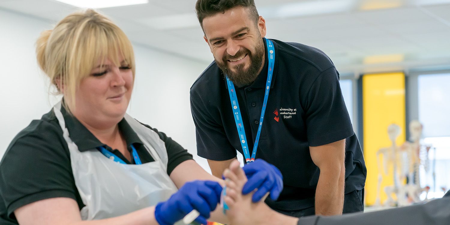 Two podiatry apprentices practising on a foot