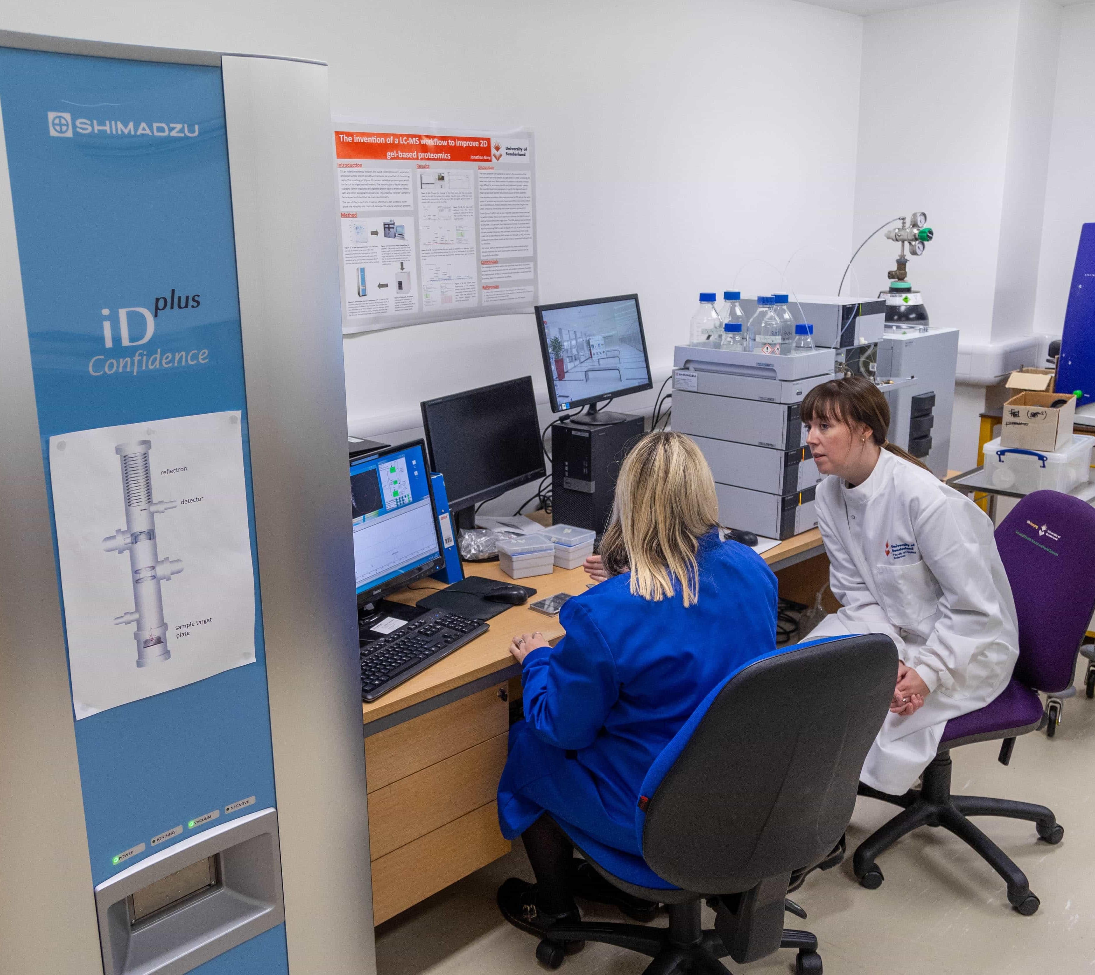 students in the lab using the computer equipment wearing lab coats