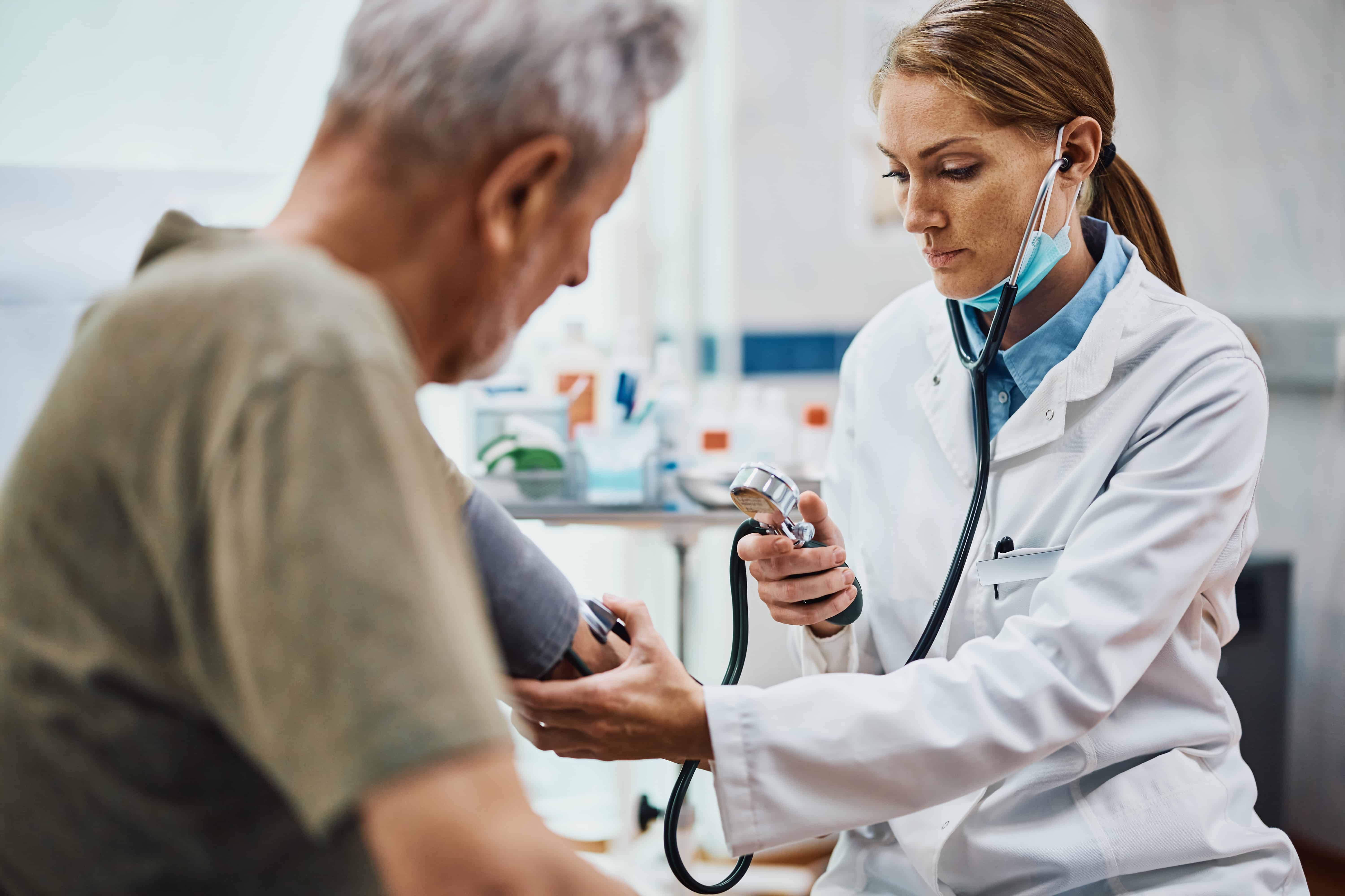 healthcare professional in white coat using a stethoscope on a patient