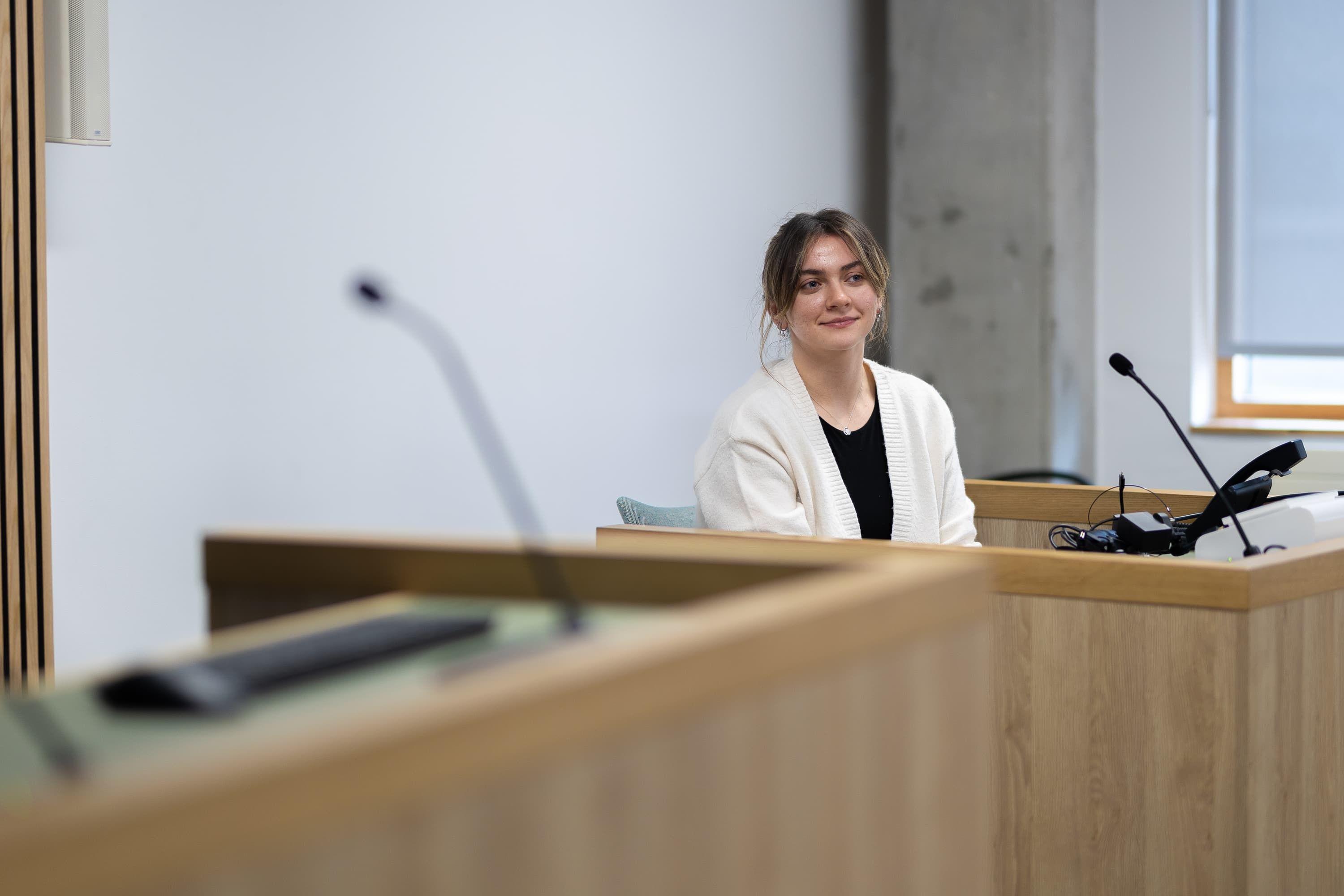 A student sitting in the witness box looking engaged in the moot court