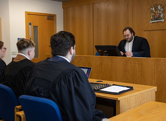 A group of students in the mock law court. There is a judge's area and seating in front of it.