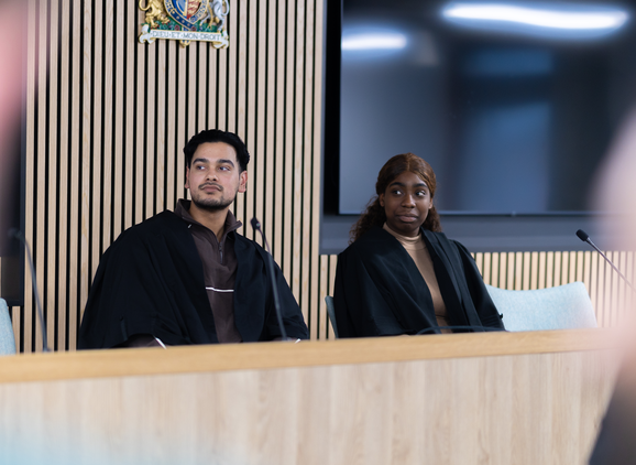 Two students sitting at the front of the mock law court looking into the distance