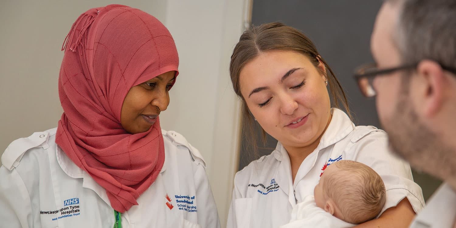 Midwifery students holding a baby