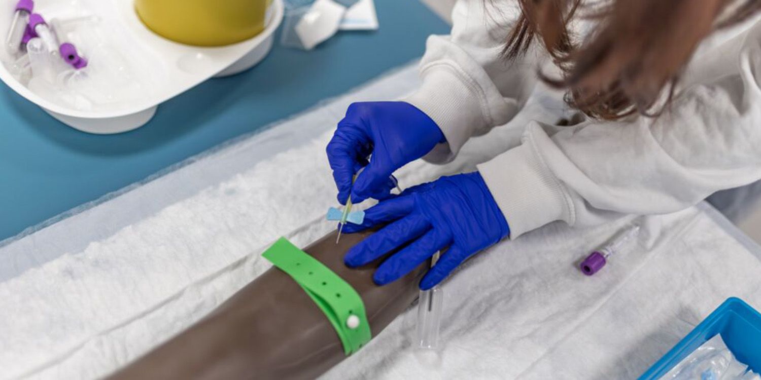 A gloved student nurse performing an arm simulation