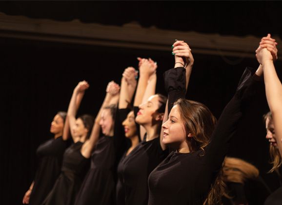 Performing Arts students standing in a line holding hands in the air
