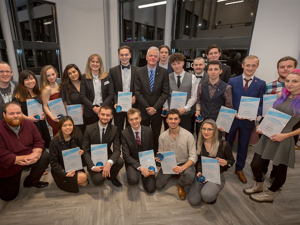 A large group of students and the Vice Chancellor standing together for a group shot, smiling for the camera. The students are holding certificates and trophies.