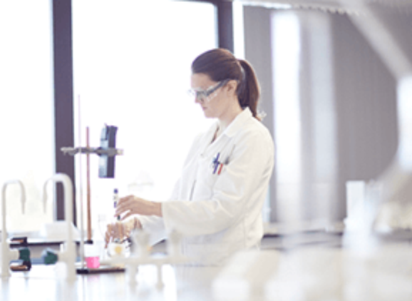student in a white lab coat working with chemicals