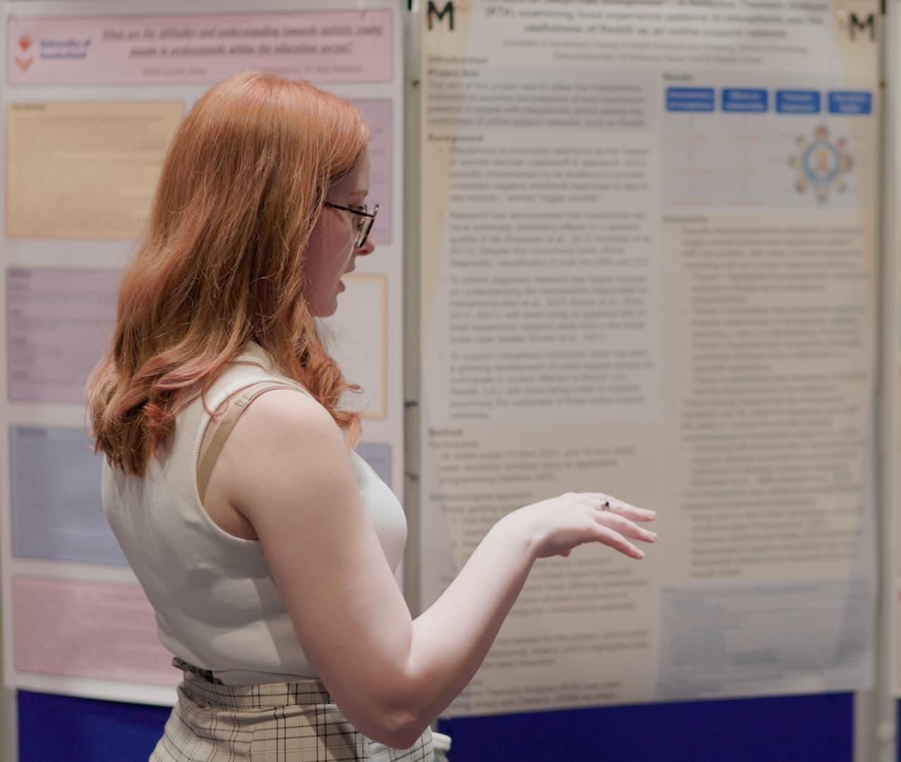 a psychology student looking at and discussing a poster at the poster presentation 2023 for the psychology final project