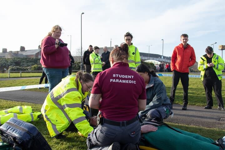 Paramedic students attending to a patient alongside policing students during a simulation day
