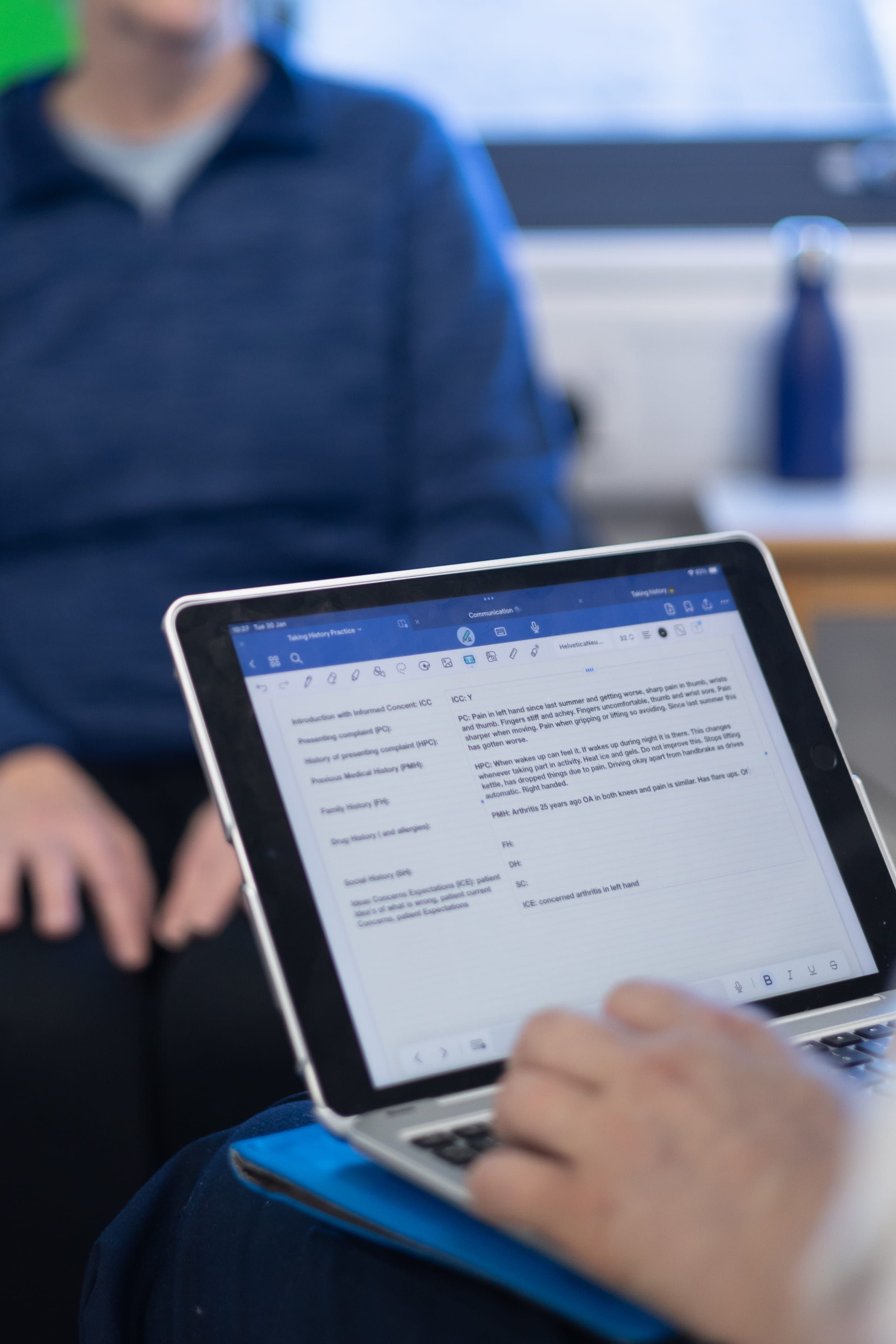 a close up shot of a physiotherapy student using a laptop to take notes while speaking with a PCPI patient