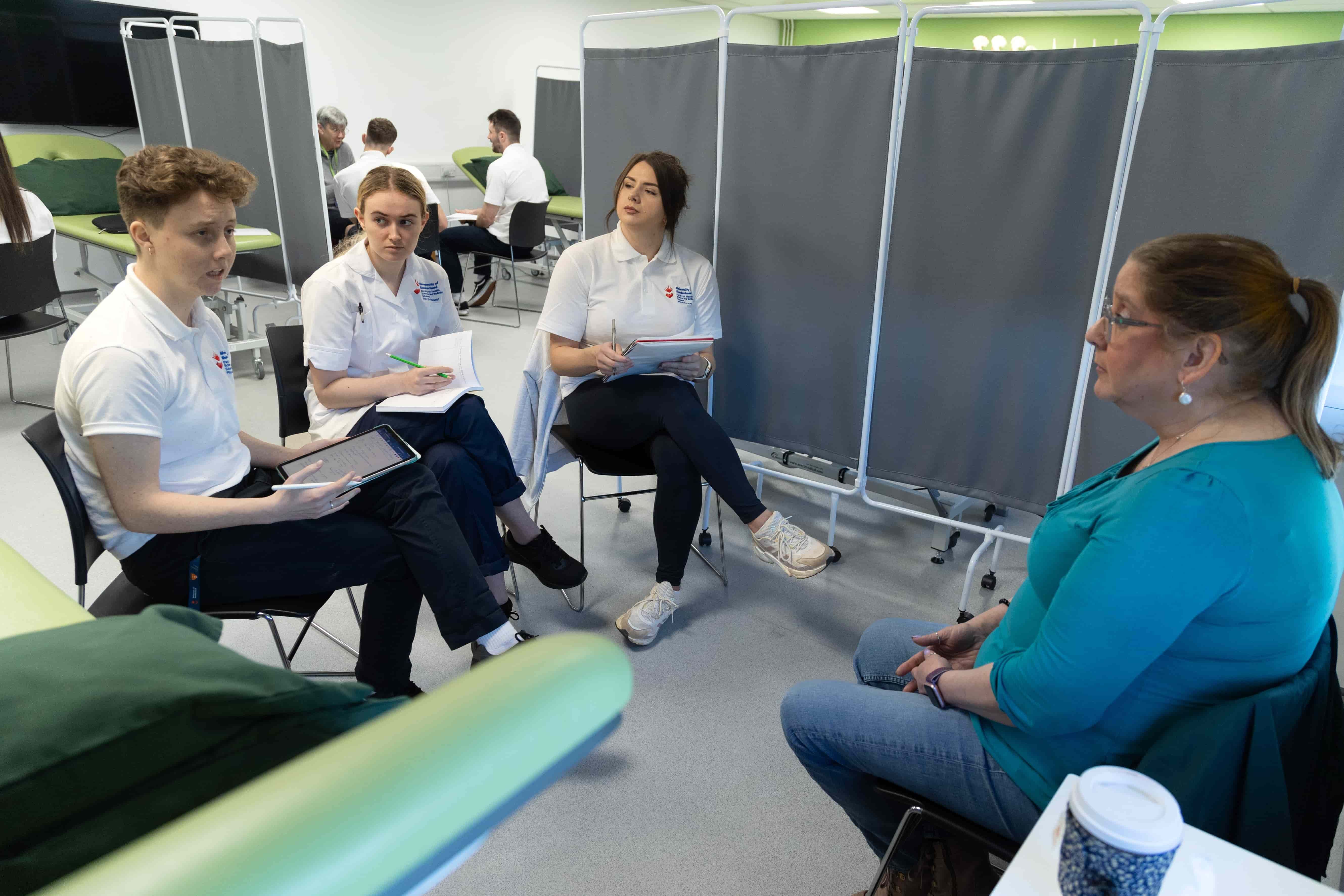 Three physiotherapy students speaking with a PCPI member during a session