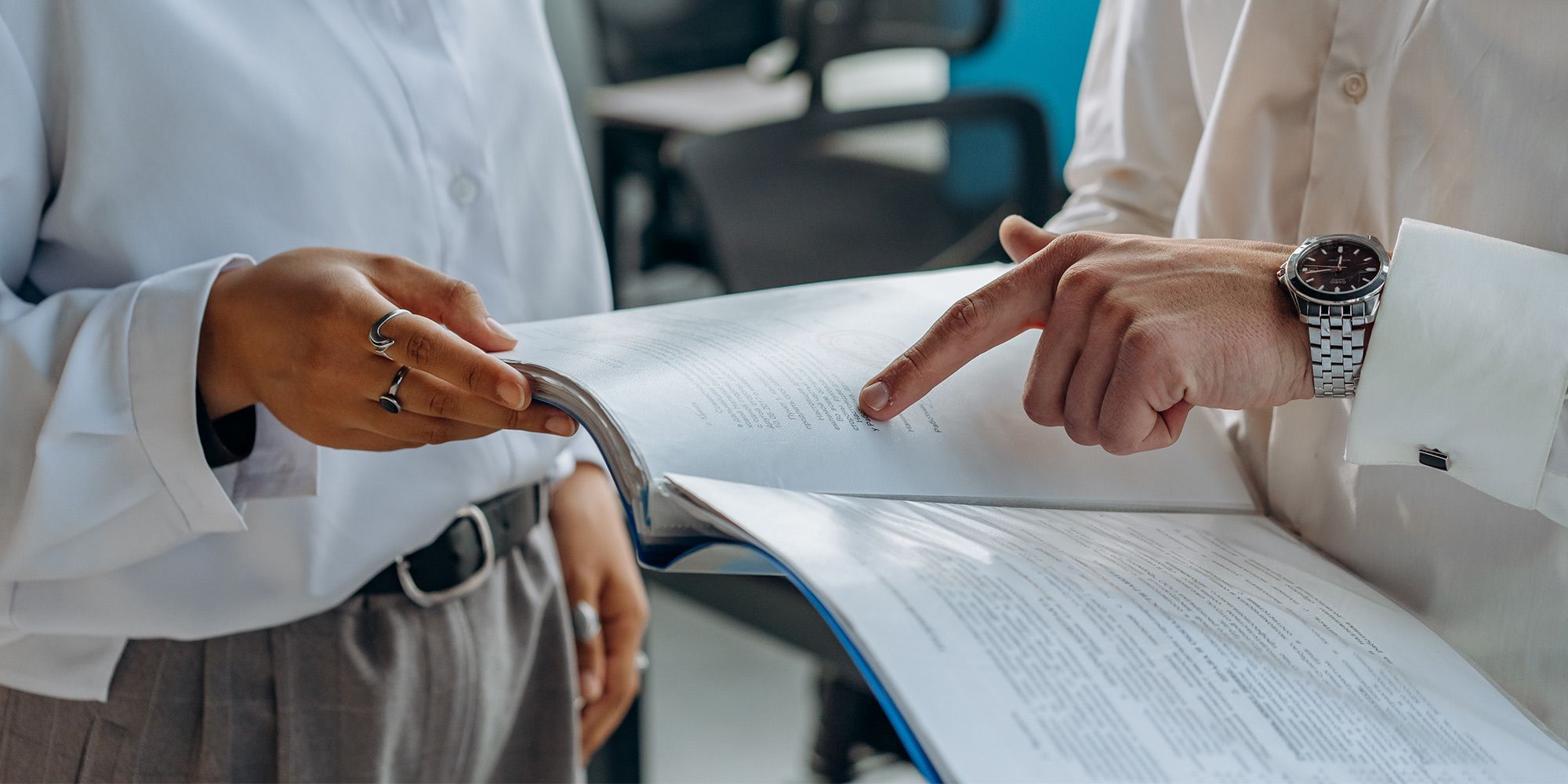 Two people with hands pointing at a document