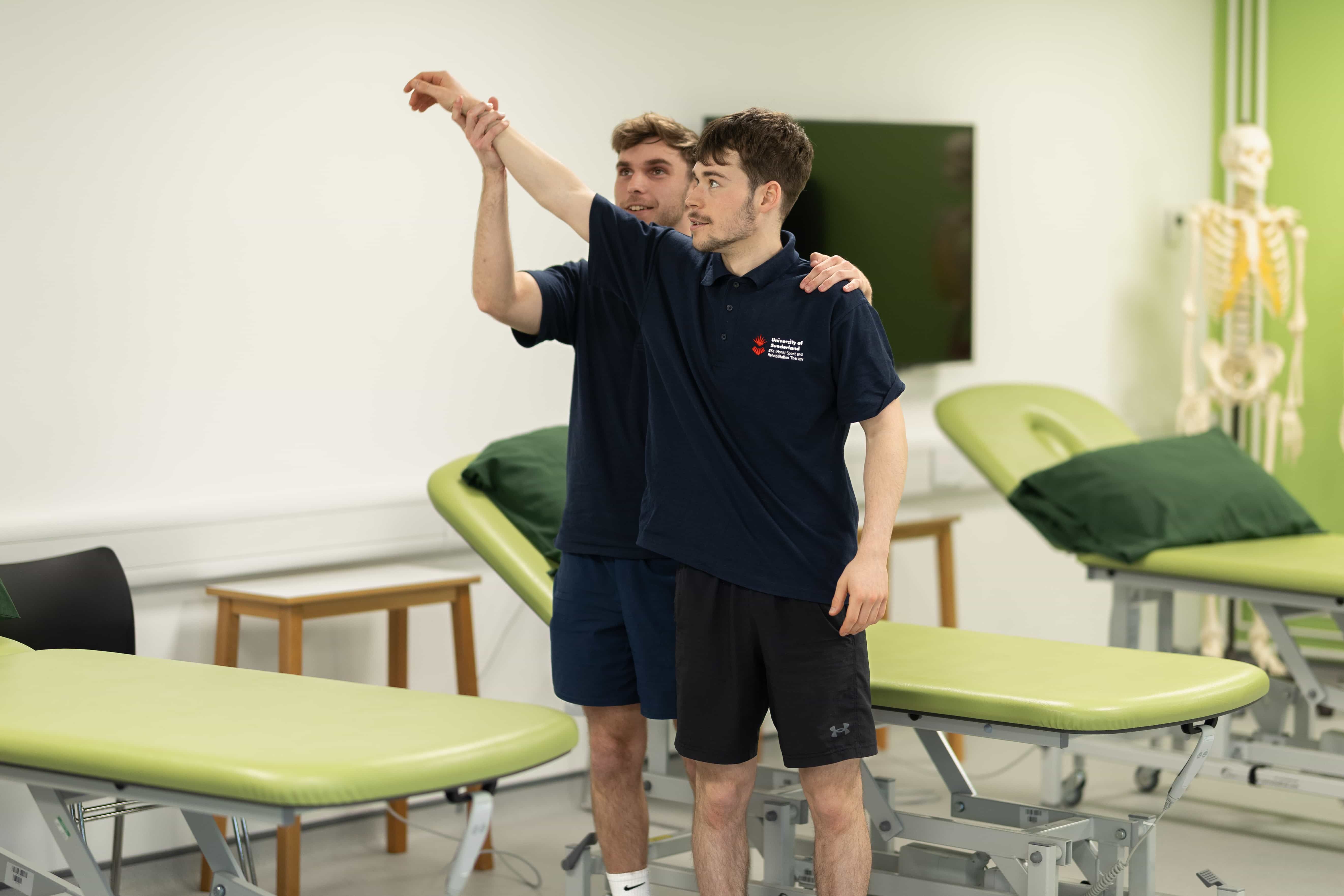 A student guiding another student stretching their arm