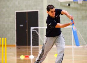 A student playing cricket in the sports hall