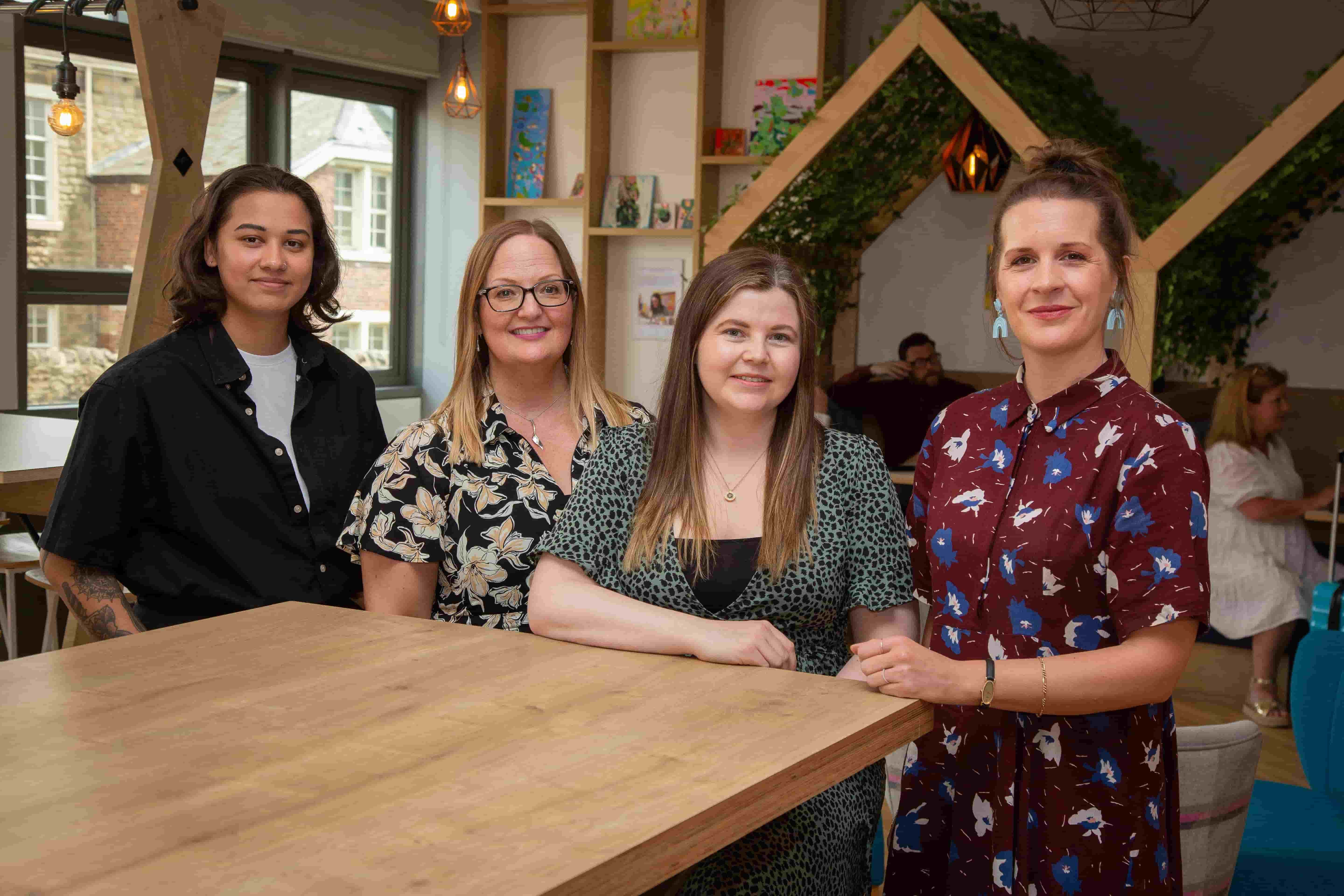 The We Care team, including Safeenah, Wendy, Lauren, and Jess, standing around a table