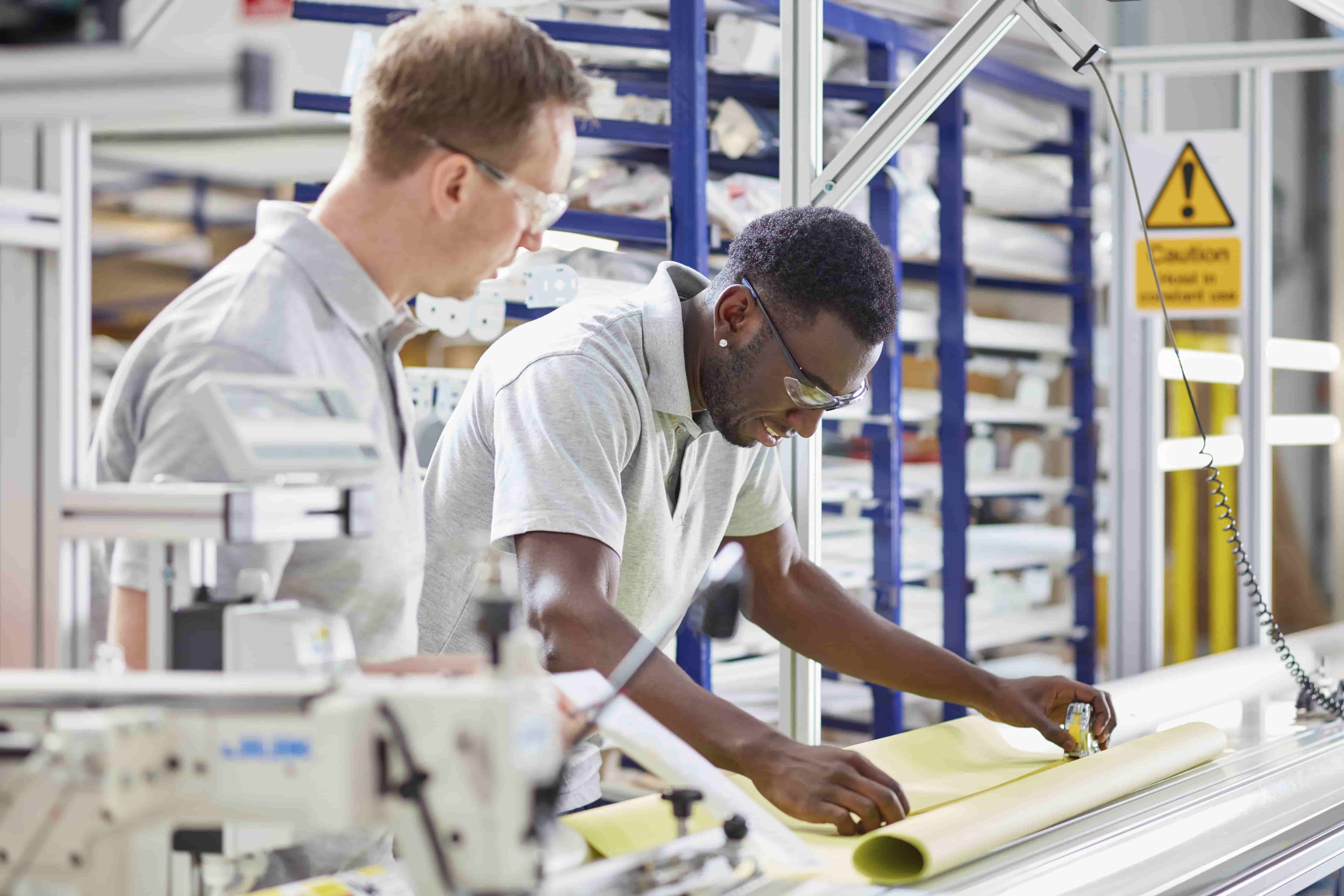 A mentor assisting an employee with their work in a workshop