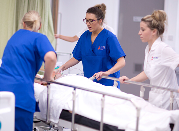 A group of nurses surrounding a hospital bed